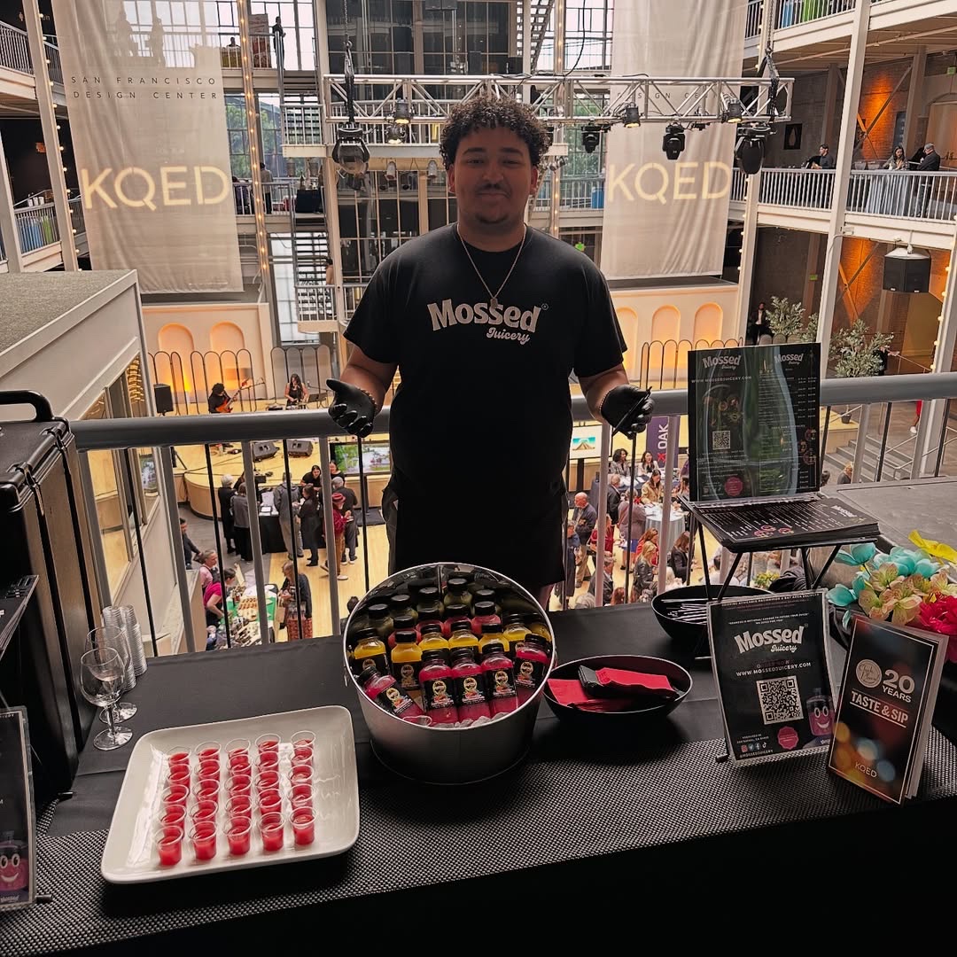 Mossed Juicery team member serving colorful cold-pressed juice samples at the event booth