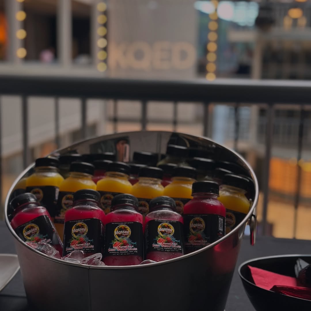 Close view of colorful Mossed Juicery bottles chilled on ice at a community event